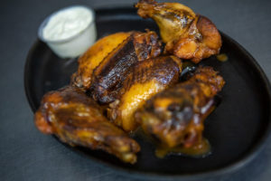 chicken wings with ranch dressing on a black plate